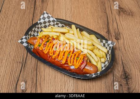 Gros plan d'un hot-dog recouvert de Chili con carne épicé, de nachos écrasés pour le croquant, d'oignons rouges marinés et d'une généreuse cuillère de crème sure fraîche. Banque D'Images