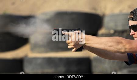 Tireur professionnel tirant d'une arme de poing, vue latérale, gros plan Banque D'Images