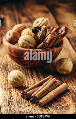 Les bâtons de cannelle et les limes à bol en bois sur table rustique Banque D'Images