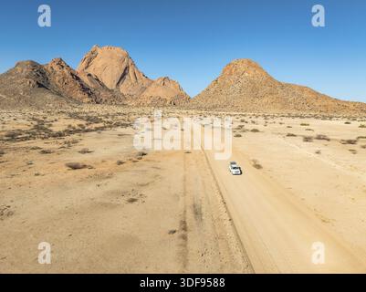Vue aérienne, voiture sur route sablonneuse, montagnes dans le désert, sommet du Spitzkoppe, désert du Namib, Namibie Banque D'Images