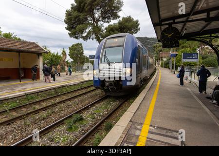 Eze, France -22 décembre 2025 : un train de transport express régional (TER) par SNCF arrive à la gare d'Eve en provenance de Monaco. Banque D'Images