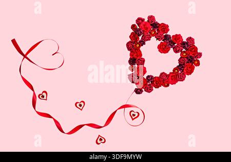 Couronne romantique de rose rouge en forme de coeur avec ruban sur fond rose pour la Saint-Valentin Banque D'Images