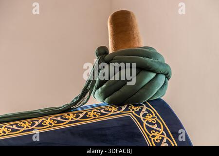Le tombeau (türbe) d’Emir Celaleddin Karatay dans la médersa Karatay (Karatay Medresesi) à Konya, en Turquie, est orné d’un chapeau mevlevi et d’une écharpe verte. Le vizir seldjoukide Karatay (décédé en 1254) a fait construire l’ancienne collège islamique en 1251. Depuis 1954, le bâtiment sert de musée de carreaux (Musée des œuvres de carrelage de Konya). Banque D'Images