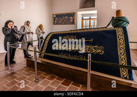 Le tombeau (türbe) d’Emir Celaleddin Karatay dans la madrasa Karatay (Karatay Medresesi) à Konya, en Turquie, est observé par des visiteurs étudiant sa calligraphie. Le vizir seldjoukide Karatay (décédé en 1254) a fait construire l’ancien collège islamique en 1251. Depuis 1954, le bâtiment sert de musée de carreaux (Konya Tile Works Museum). Banque D'Images