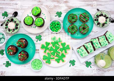 Desserts à thème de la St Patricks Day. Scène de table sur un fond de bois blanc. Biscuits Shamrock, cupcakes verts, brownies, beignets et bonbons. Vue de dessus Banque D'Images