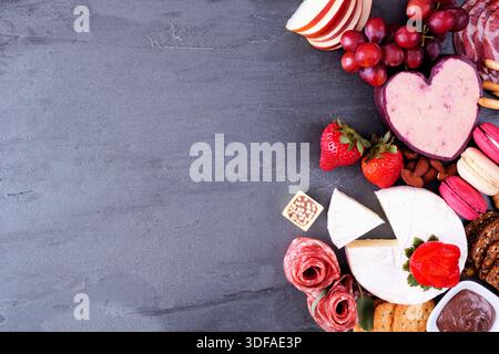 Bordure latérale charcuterie thème Saint-Valentin. Vue de haut en bas sur un fond d'ardoise sombre. Copier l'espace. Banque D'Images