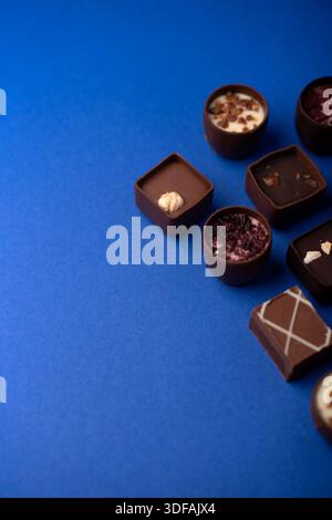 vue rapprochée de haut en bas de pralines et truffes artisanales au chocolat disposées sur une surface d'atelier bleu cobalt éclatante, mettant en valeur le brun riche Banque D'Images