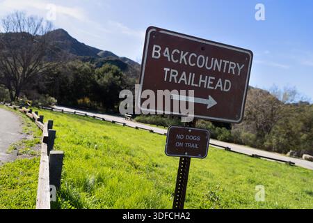 Un panneau marquant le début du sentier de l'arrière-pays au Malibu Creek State Park en Californie, avec des collines ondulantes et des prairies ouvertes en arrière-plan. Banque D'Images