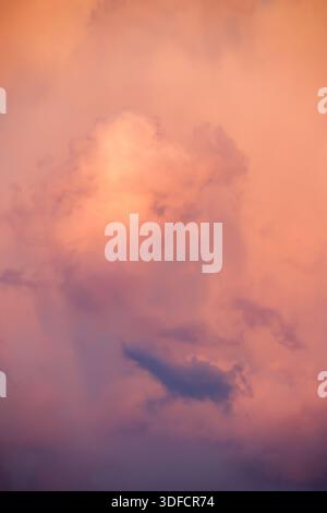 Une composition verticale et éthéré se concentrant sur les textures de nuages doux, roses et oranges pendant l'heure bleue, créant une atmosphère rêveuse et artistique Banque D'Images