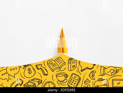 Avion de papier jaune volant sur un fond jaune avec des gribouilles d'affaires représentant de nouvelles idées et projets Banque D'Images