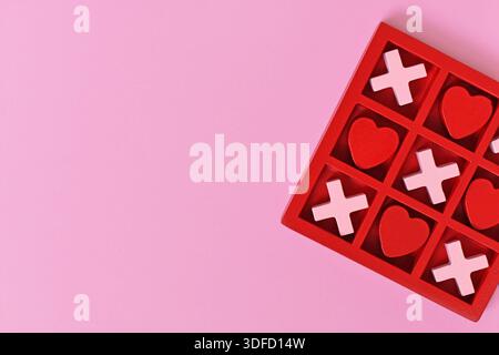 Jeu de coeur sur le thème de la Saint-Valentin avec des coeurs rouges et roses et des X dans une boîte rouge sur un fond rose avec espace de copie Banque D'Images