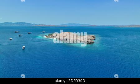 Une île bordée de sable solitaire se trouve au milieu du bleu infini de Komodo, une halte parfaite pour les plongeurs et les chasseurs de coucher de soleil Banque D'Images