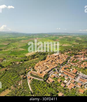 Vue aérienne sur les toits baignés de soleil et le majestueux Duomo projetant des ombres sur les rues anciennes, niché au milieu des collines verdoyantes de Toscane, P. Banque D'Images
