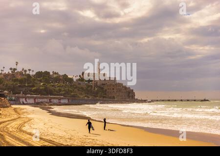 Silhouettes de surfeurs sur la plage de tel Aviv avec horizon de Jaffa Banque D'Images