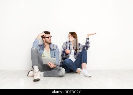 Couple shopping en ligne, assis sur le sol à la maison Banque D'Images