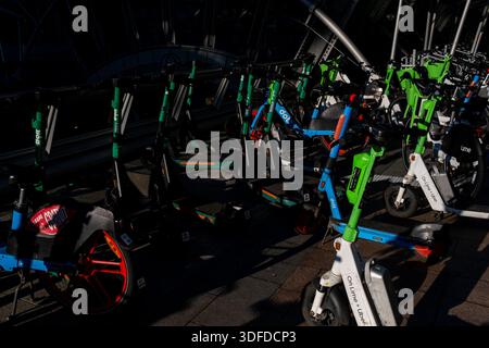 Des rangées de scooters électriques partagés et de vélos de location portant les marques Bird, Lime et DOTT avec les textes Uber et ESSAI GRATUIT sont garées le long d’un trottoir à Bruxelles, B. Banque D'Images