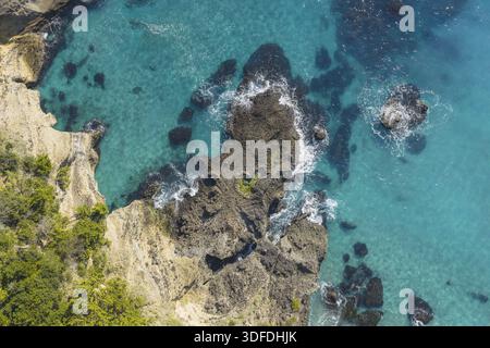 Vue aérienne des roches accidentées rencontrent la mer turquoise dans la grotte de la mer de Ryugu, créant un contraste saisissant de textures et de couleurs, Shimoda, Shizuoka, Japon. Banque D'Images