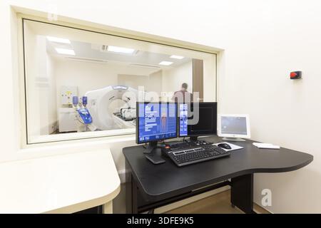 Une salle de numérisation avec ordinateurs et moniteurs à côté de la salle de tomodensitométrie dans un nouvel hôpital moderne de traitement du cancer Banque D'Images