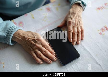 Femme âgée utilisant un smartphone à la maison Banque D'Images
