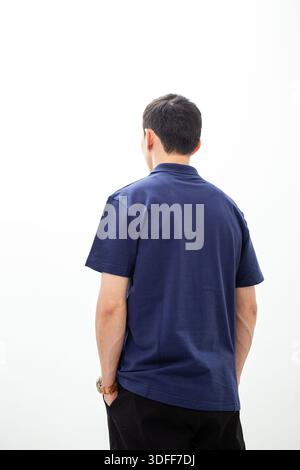 Vue arrière de l'homme en polo bleu marine sur fond blanc. Banque D'Images