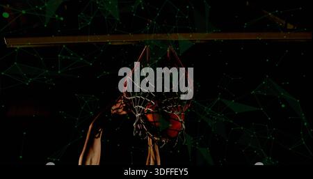 Joueur de maillot sans manches qui saisit le bord pendant que la balle entre dans le cerceau sur le terrain, avec revêtement vert Banque D'Images