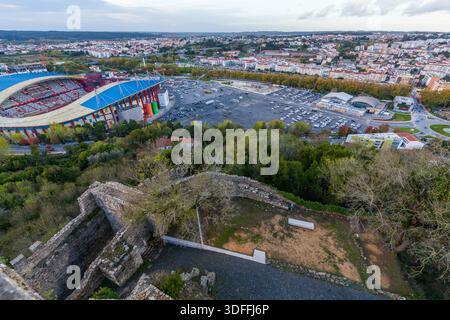 Leiria. ramed par les anciens remparts en pierre altérés d'un château, une vue panoramique capture un stade moderne avec un toit bleu vif niché avec Banque D'Images