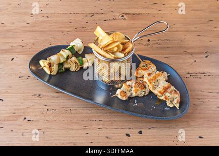 brochettes de poulet mariné grillé, avec des morceaux juteux entrecoupés de poivrons rouges et verts, servies sur un généreux lit de romarin rôti Banque D'Images