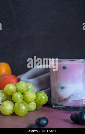Une nature morte qui joue avec les transparences : des fruits rouges à l’intérieur d’un bocal en verre rempli d’eau, créant un effet grossissant, aux côtés d’un semi-transparent Banque D'Images