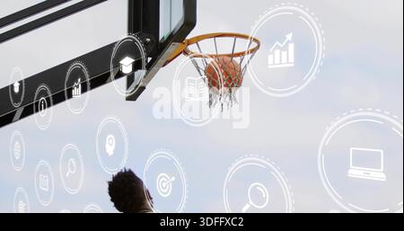 Atteindre un mâle dans un réservoir sombre attrapant le basket-ball pris dans le filet au cerceau extérieur avec des icônes superposées Banque D'Images