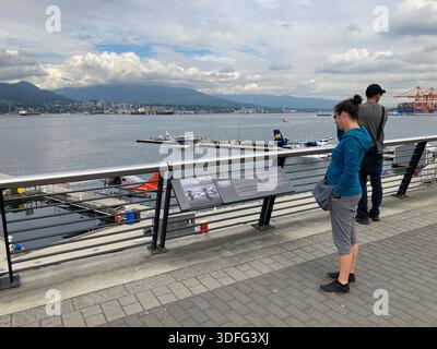 Les touristes apprécient la vue sur le port de Vancouver avec des hydravions amarrés à la jetée et les montagnes de la rive nord en arrière-plan. Banque D'Images