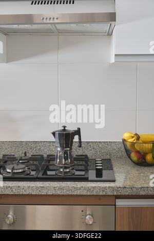 Pot de moka traditionnel assis sur une cuisinière à gaz dans une cuisine avec comptoir en granit Banque D'Images
