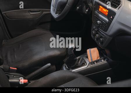 Intérieur de la voiture montrant un portefeuille brun dans la console entre les sièges et les commandes Banque D'Images