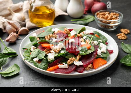 Délicieuse salade avec betterave, épinards, fromage, noix et carotte sur table noire, gros plan Banque D'Images