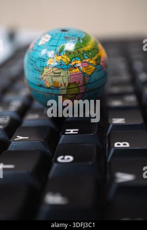 Un petit globe placé sur un clavier d'ordinateur, mettant en évidence l'Afrique et l'Europe, symbolisant la connectivité et la technologie mondiales Banque D'Images