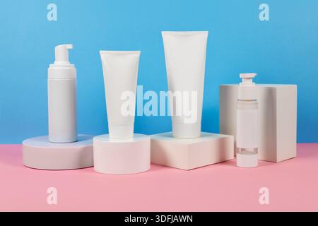 Beaux modèles cosmétiques pour les annonces, tubes de crème en plastique et bouteilles sur un fond bleu avec des podiums. Design esthétique pour un produit haut de gamme Banque D'Images