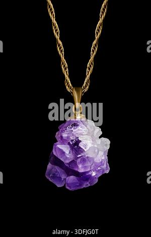 Grand pendentif cristal améthyste sur chaîne dorée isolé sur noir Banque D'Images