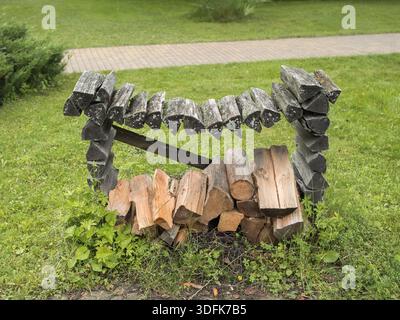 Bûches de bois de chauffage soigneusement empilées dans une pile de bois construite à partir de bûches, placées à l'extérieur sur de l'herbe verte fraîche Banque D'Images