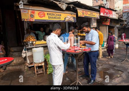 Old Delhi, Delhi, Inde - 31 octobre 2025 : les clients mangent des pâtisseries frites indiennes fraîches Kachoris chez un vendeur de rue à Old Delhi Inde Banque D'Images
