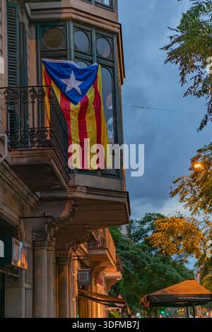 Barcelone, Espagne - 20 octobre 2025 : drapeau Estelada suspendu à un balcon sur un immeuble résidentiel au crépuscule. Banque D'Images
