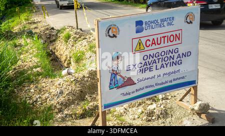Signe d'avertissement de Bohol Water Utilities, Inc., indiquant les travaux de construction en cours, d'excavation et de pose de tuyaux, Philippines Banque D'Images
