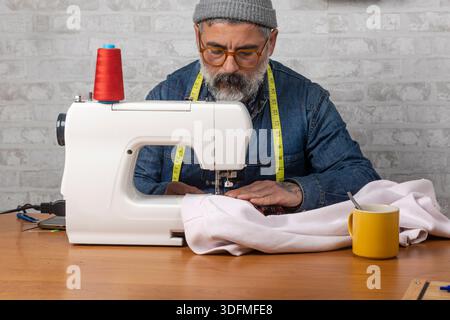 Tailleur de créateur de mode travaillant sur la machine à coudre en atelier Banque D'Images