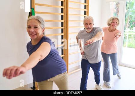 Les adultes âgés font des exercices de bras dans un centre de réadaptation en utilisant de l’équipement de physiothérapie pour améliorer leur récupération et leur mobilité. Ce gymnase intérieur Banque D'Images