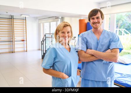Portrait de deux physiothérapeutes souriants en uniformes bleus debout dans un centre de réadaptation les professionnels de la santé sont prêts à fournir des soins de santé et reh Banque D'Images