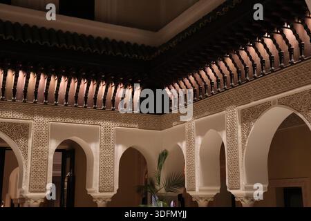 Arches en fer à cheval et éléments de plafond en bois sculptés avec art dans une cour de la Mamounia à Marrakech, Maroc Banque D'Images