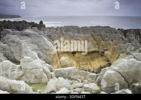 Vue sur les formations calcaires en couches sculptées par le vent et la mer, créant un paysage surréaliste sur la toile de fond de l'océan, Punakaiki, West Coast Reg Banque D'Images