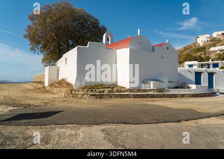 Vue d'une église blanche et dure avec un toit rouge vif se dresse fièrement contre le ciel Azur, une scène classique de l'architecture grecque, Mykonos, Grèce. Banque D'Images