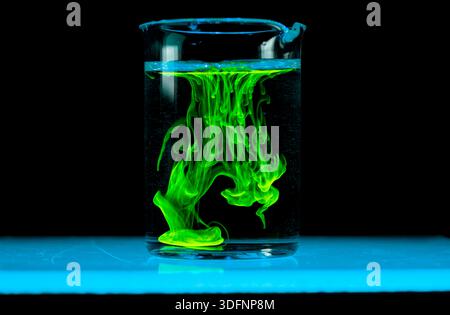 Dissolution et étalement d'une substance verte dans un flacon avec un liquide clair. Réaction chimique observée en laboratoire. Copyspace. Banque D'Images