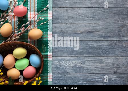 Oeufs colorés disposés avec des éléments décoratifs sur une table en bois rustique Banque D'Images
