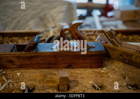 Ancien plan de main charpentier reposant sur une table en bois brut avec de la sciure de bois et des copeaux, intérieur d'atelier rustique axé sur l'artisanat en bois fait à la main Banque D'Images