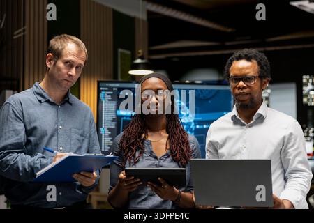 Portrait de programmeurs dans le bureau examinant les métriques du système d'IA, surveillant les tableaux de bord de performance. Des collaborateurs d'une entreprise de technologie réglant les réseaux neuronaux à l'aide d'outils sur des appareils Banque D'Images